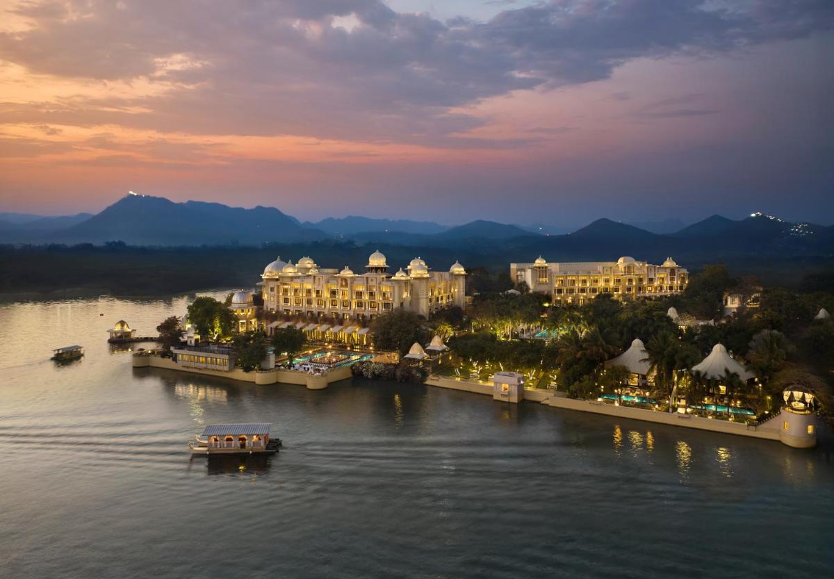 a view of a resort on the water at night at The Leela Palace Udaipur in Udaipur