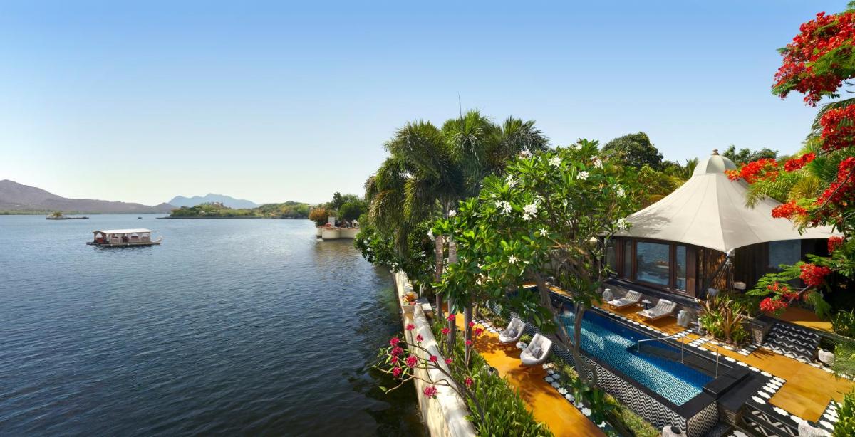 a view of a river with a house and a pool at The Leela Palace Udaipur in Udaipur