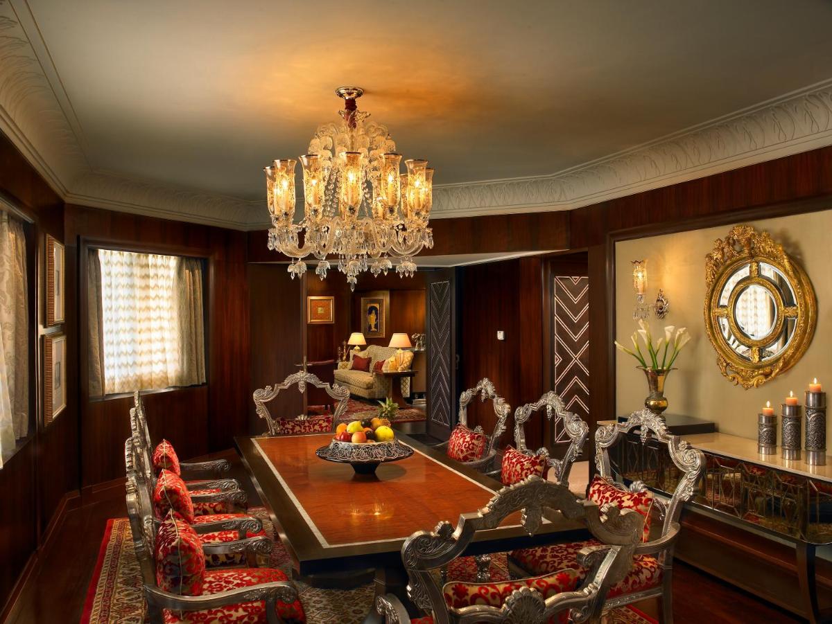 a dining room with a table and chairs and a chandelier at The Leela Palace Udaipur in Udaipur