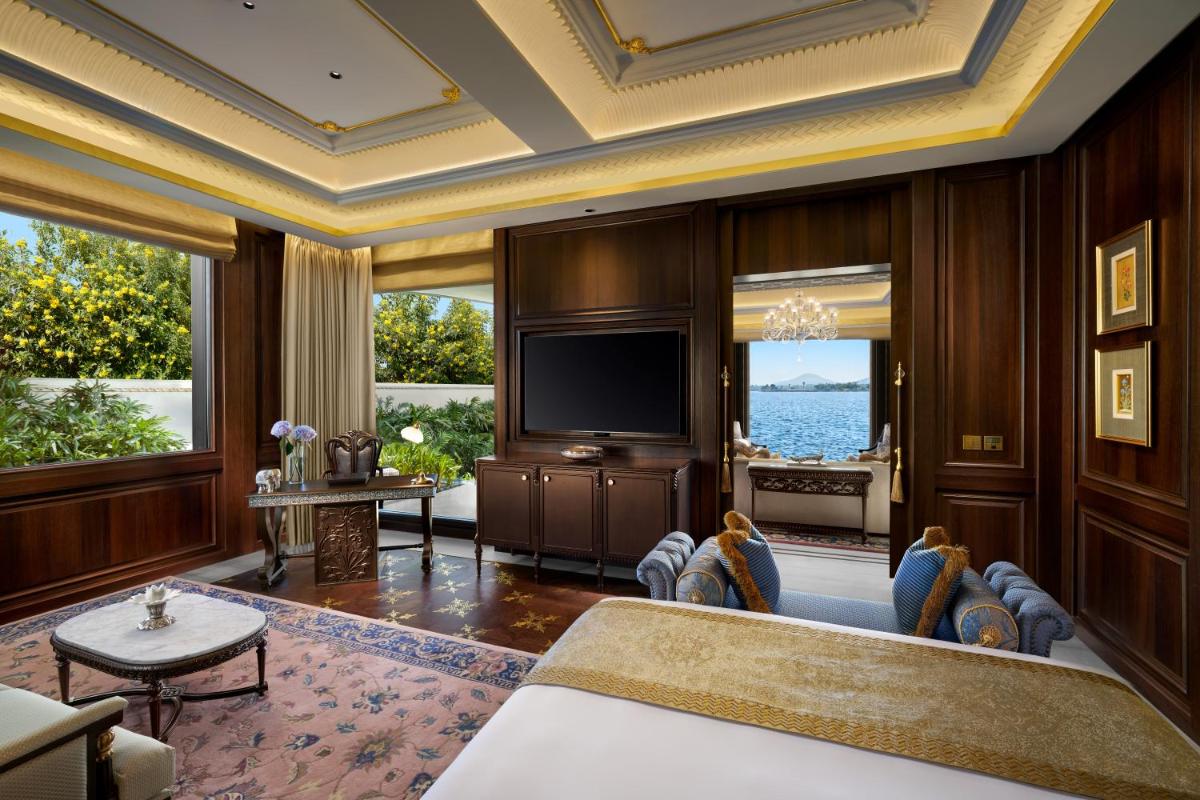 a living room with a television and large windows at The Leela Palace Udaipur in Udaipur