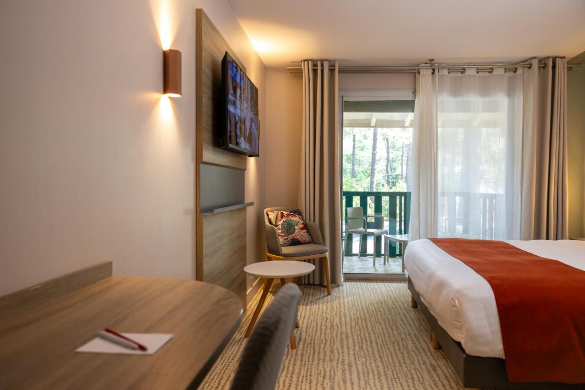 une chambre d'hôtel avec un lit, un bureau et une fenêtre dans l'établissement Hôtel & Spa Vitalparc, The Originals Collection, à Lacanau-Océan