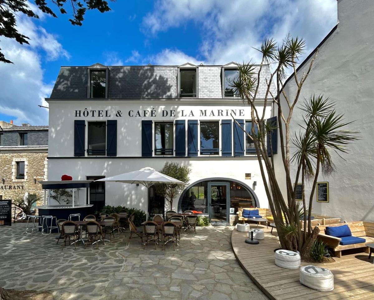 un hôtel avec des chaises et des tables en face d'un bâtiment dans l'établissement HOTEL LA MARINE, à Groix