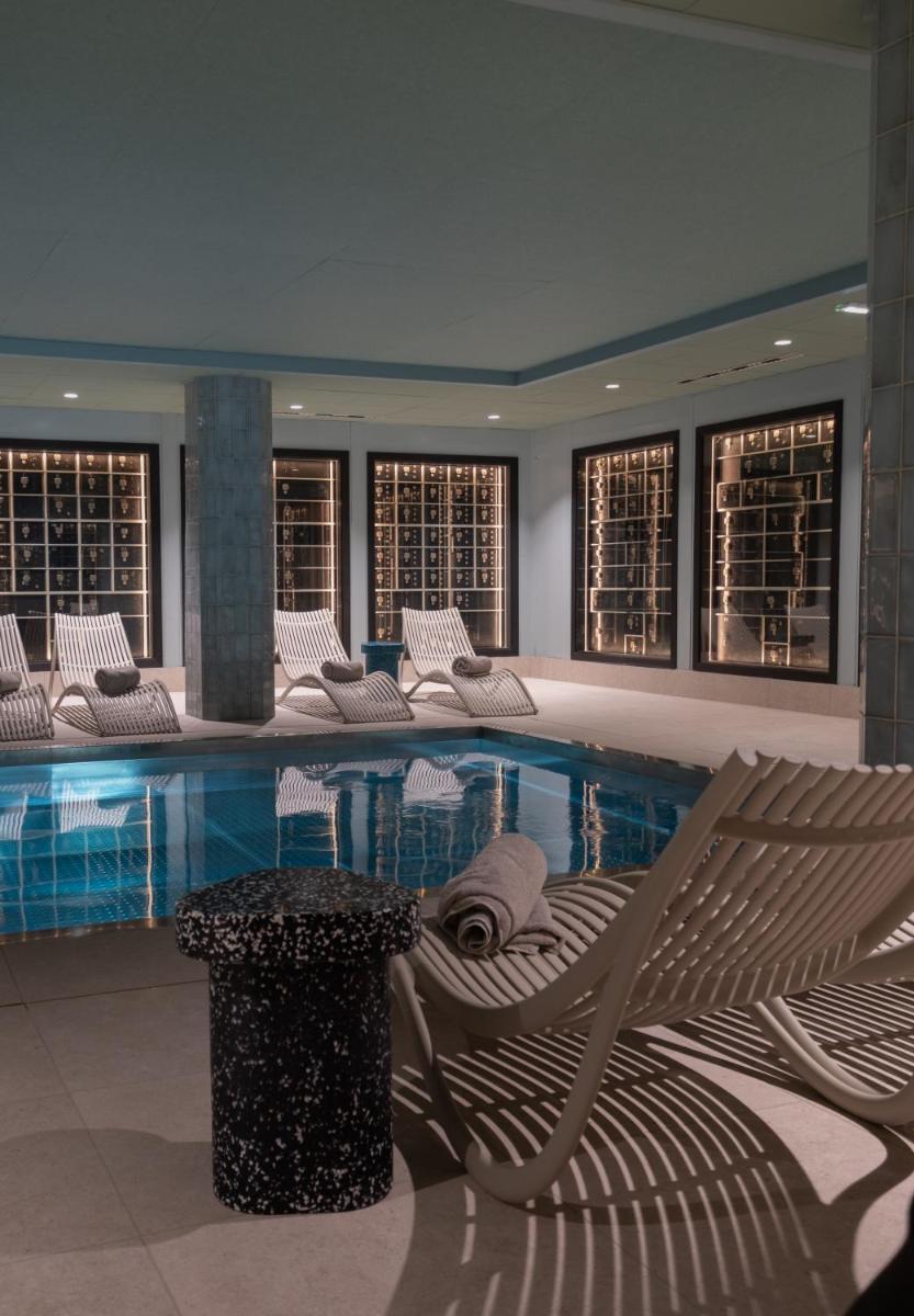 une piscine avec des chaises et un banc dans un bâtiment dans l'établissement Hotel & Spa Oceania Lille Les Augustins, à Lille