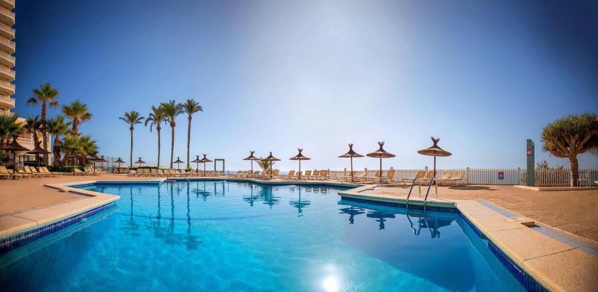 una gran piscina con palmeras y sombrillas en Hotel Servigroup La Zenia 4 Sup, en Playas de Orihuela