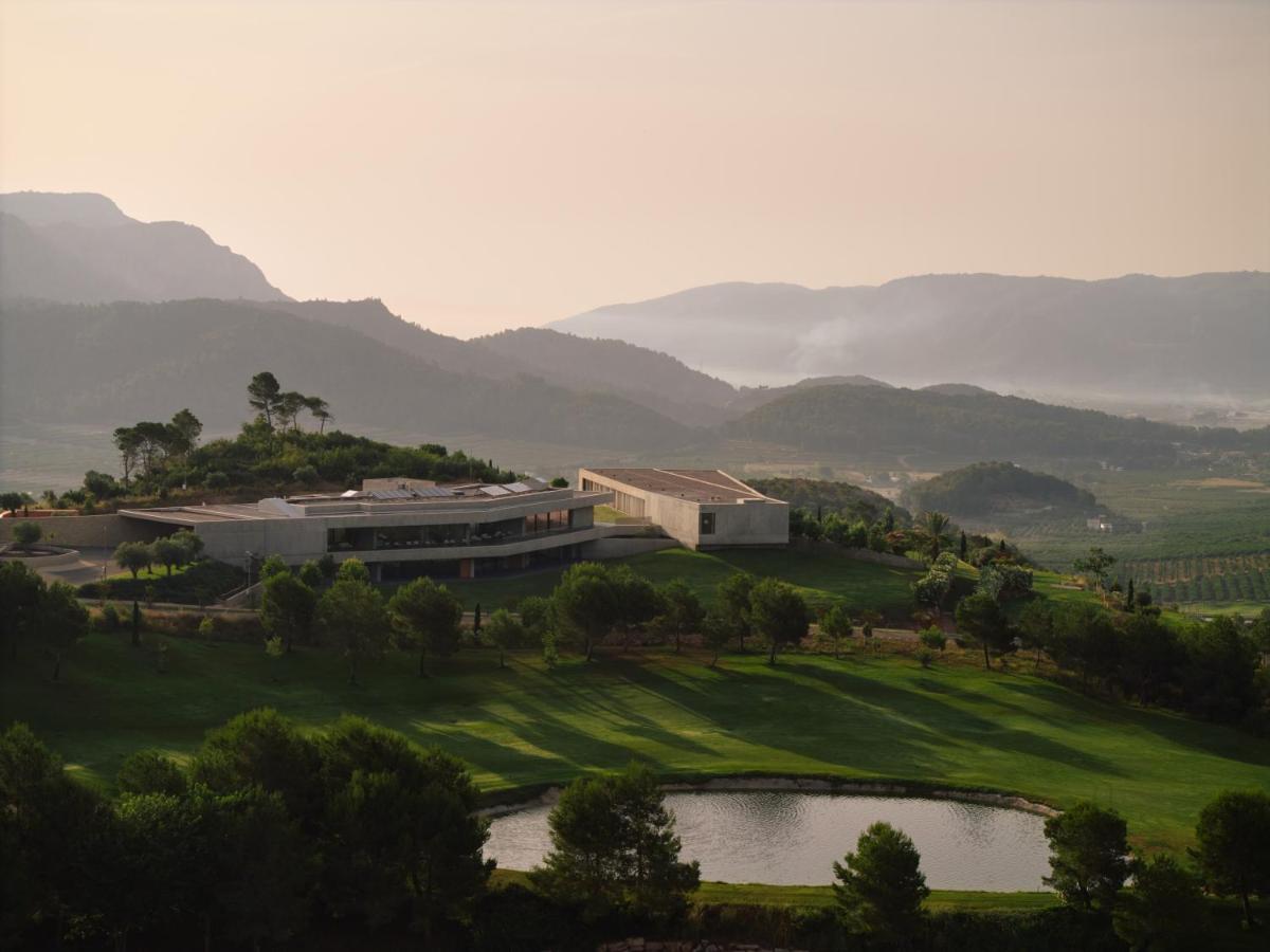 un campo de golf con un edificio y un estanque en La Galiana Golf Resort - Adults Only, en Barraca de Aguas Vivas