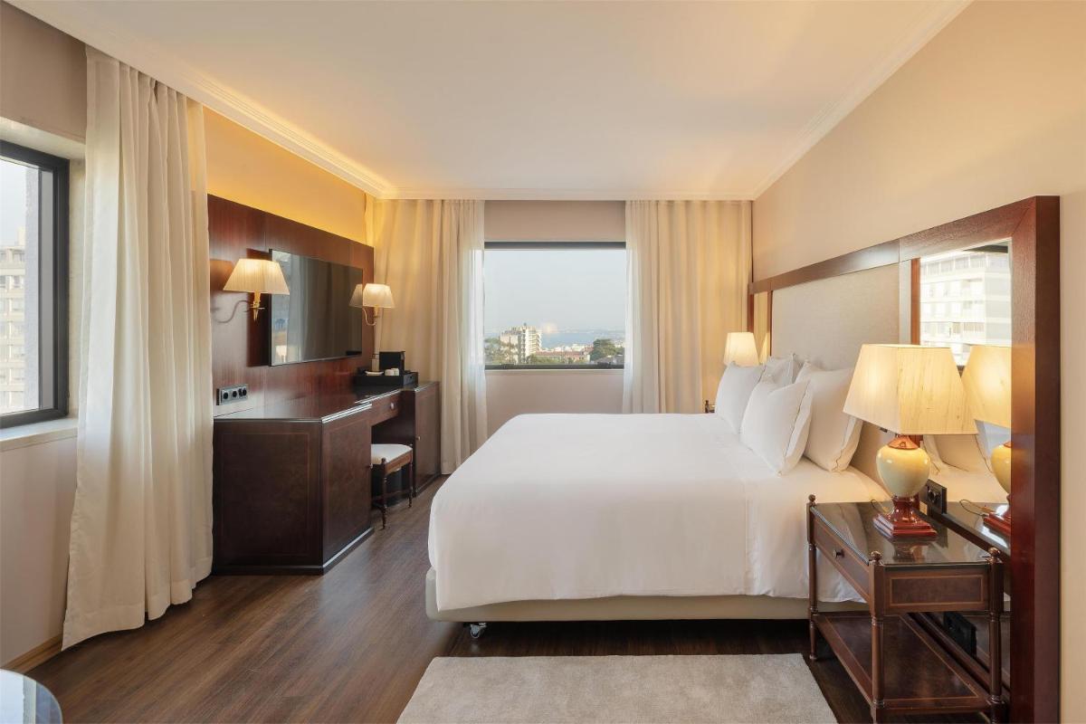 um quarto com uma grande cama branca e uma janela em Dom Pedro Lisboa Hotel, a member of Radisson Individuals em Lisboa