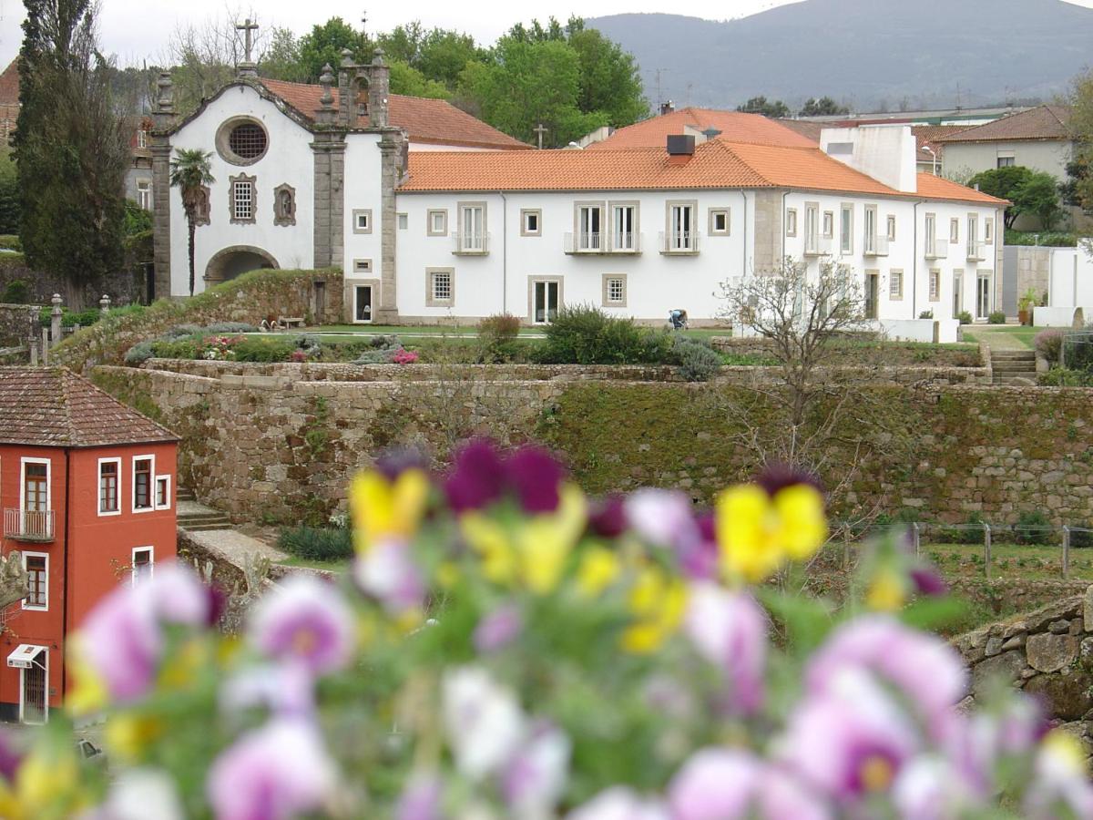 uma grande casa branca com flores em primeiro plano em Hotel Convento dos Capuchos em Monção