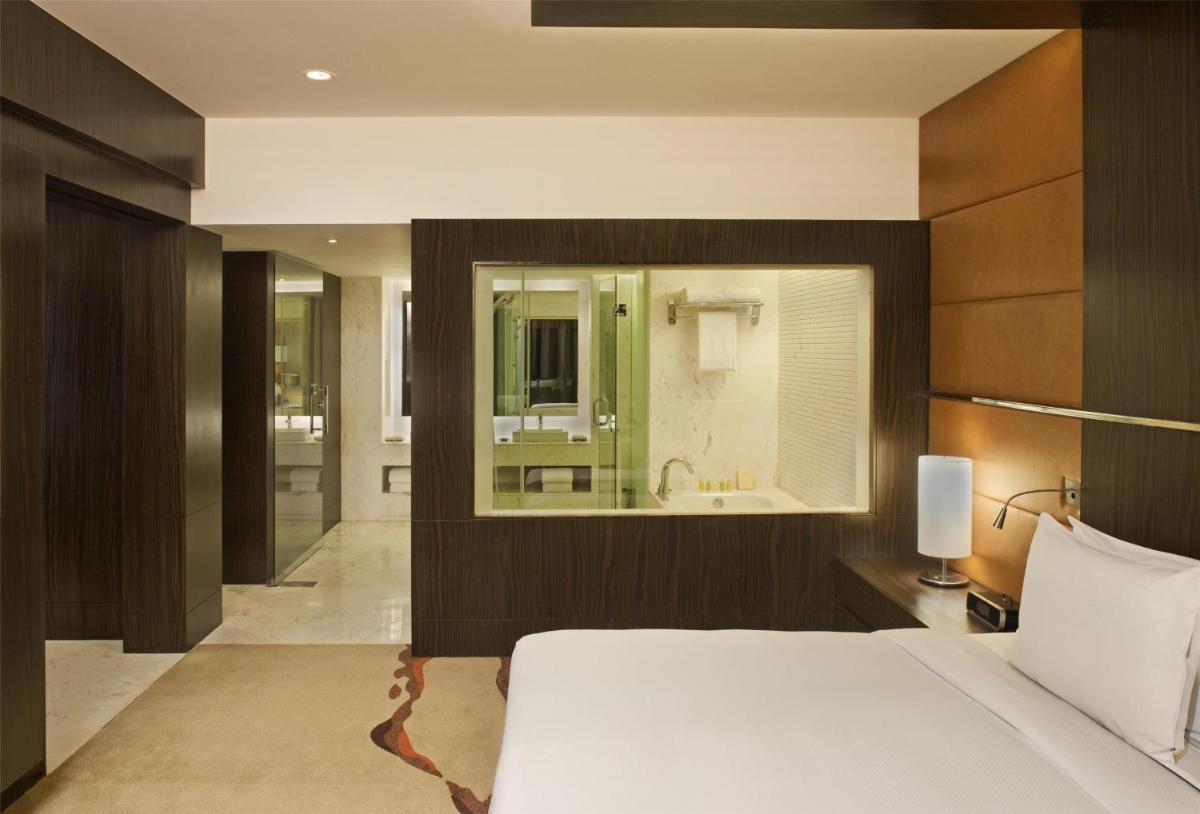 a bedroom with a large bed and a bathroom at Radisson Blu Hotel Amritsar in Amritsar
