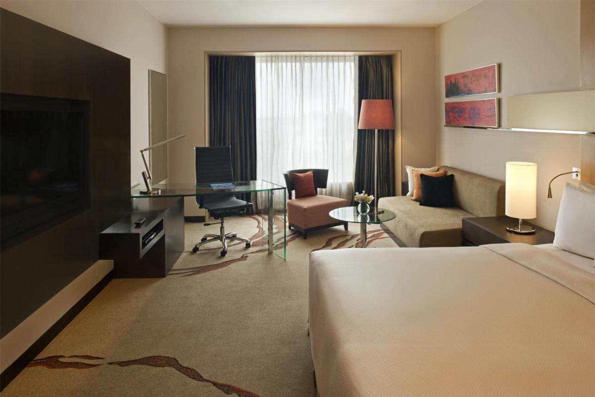a hotel room with a bed and a desk and a living room at Radisson Blu Hotel Amritsar in Amritsar