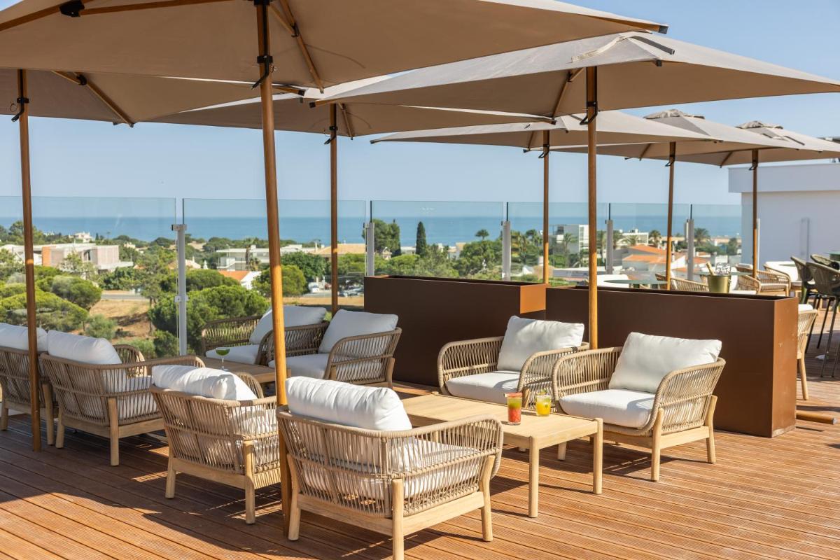 um pátio com cadeiras, mesas e guarda-sóis em Castelo Suites Hotel em Albufeira
