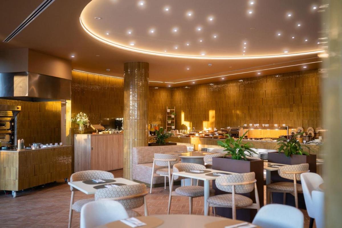 um restaurante com mesas e cadeiras e um bar em Castelo Suites Hotel em Albufeira