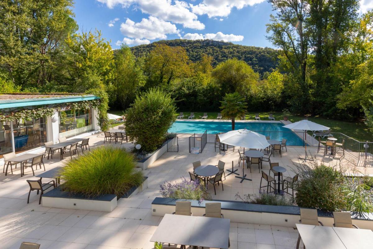 une terrasse extérieure avec tables et chaises et une piscine dans l'établissement Hôtel La Ségalière Spa Bar, à Cajarc