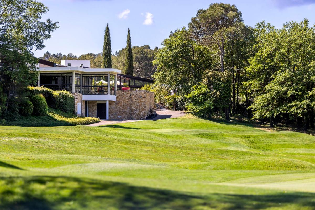 une vue d'un terrain de golf avec une maison dans l'établissement Mercure Brignoles Golf de Barbaroux & Spa, à Brignoles