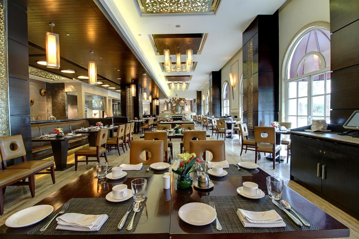 a dining room with tables and chairs in a restaurant at The Pllazio Hotel in Gurgaon