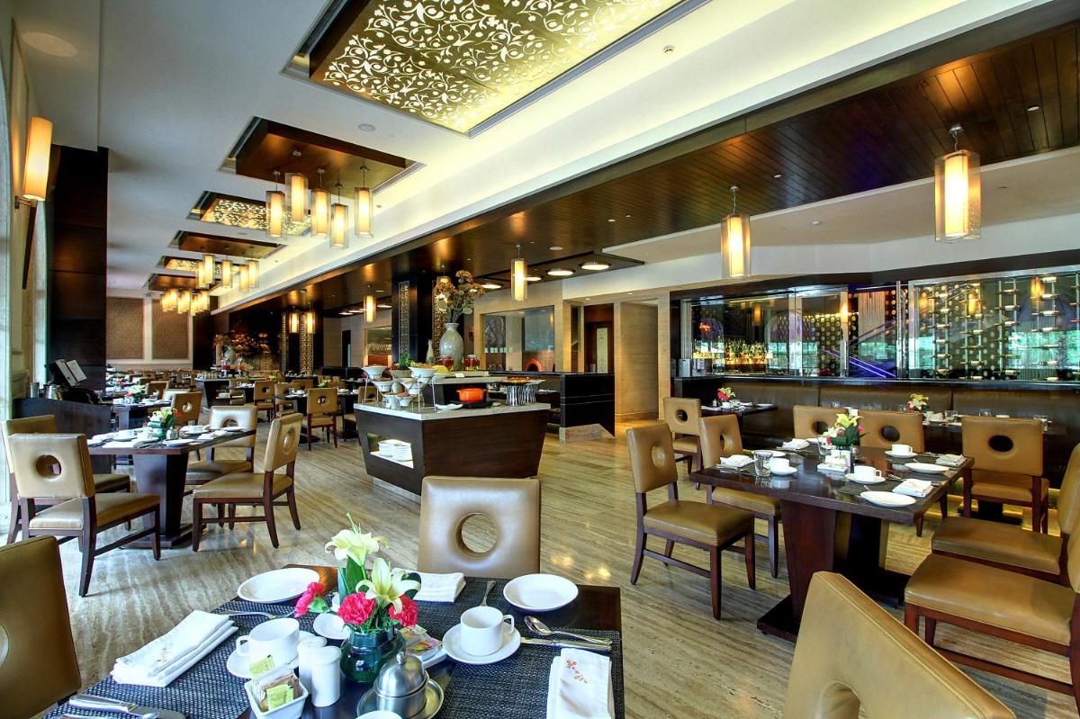 a restaurant with tables and chairs and a bar at The Pllazio Hotel in Gurgaon