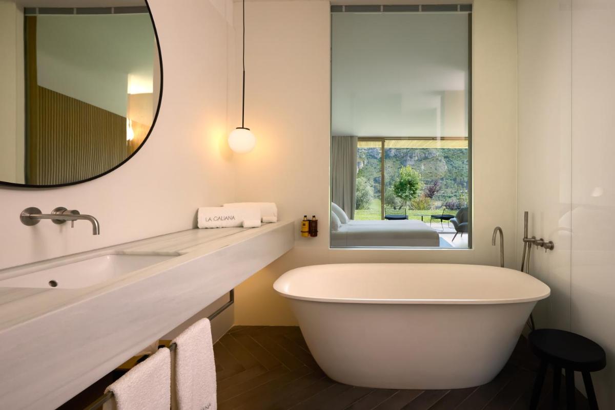 y baño con bañera blanca y espejo. en La Galiana Golf Resort - Adults Only, en Barraca de Aguas Vivas