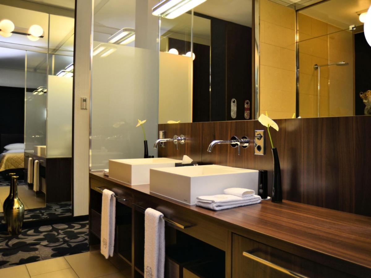 ein Badezimmer mit Waschbecken und großem Spiegel in der Unterkunft Kameha Grand Bonn in Bonn ein Badezimmer mit Waschbecken und großem Spiegel in der Unterkunft Kameha Grand Bonn in Bonn