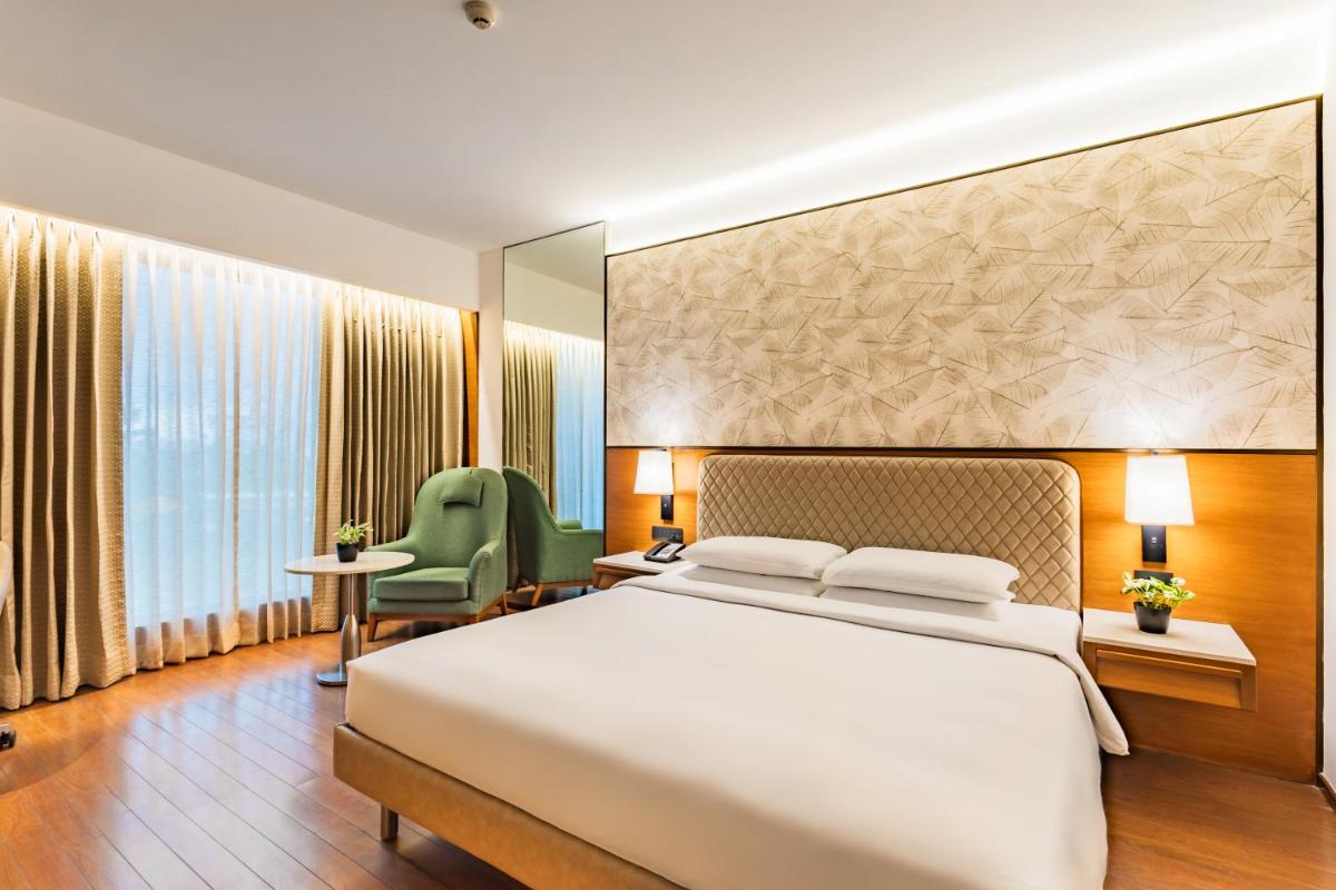 a bedroom with a large bed and a large window at Hyatt Pune in Pune