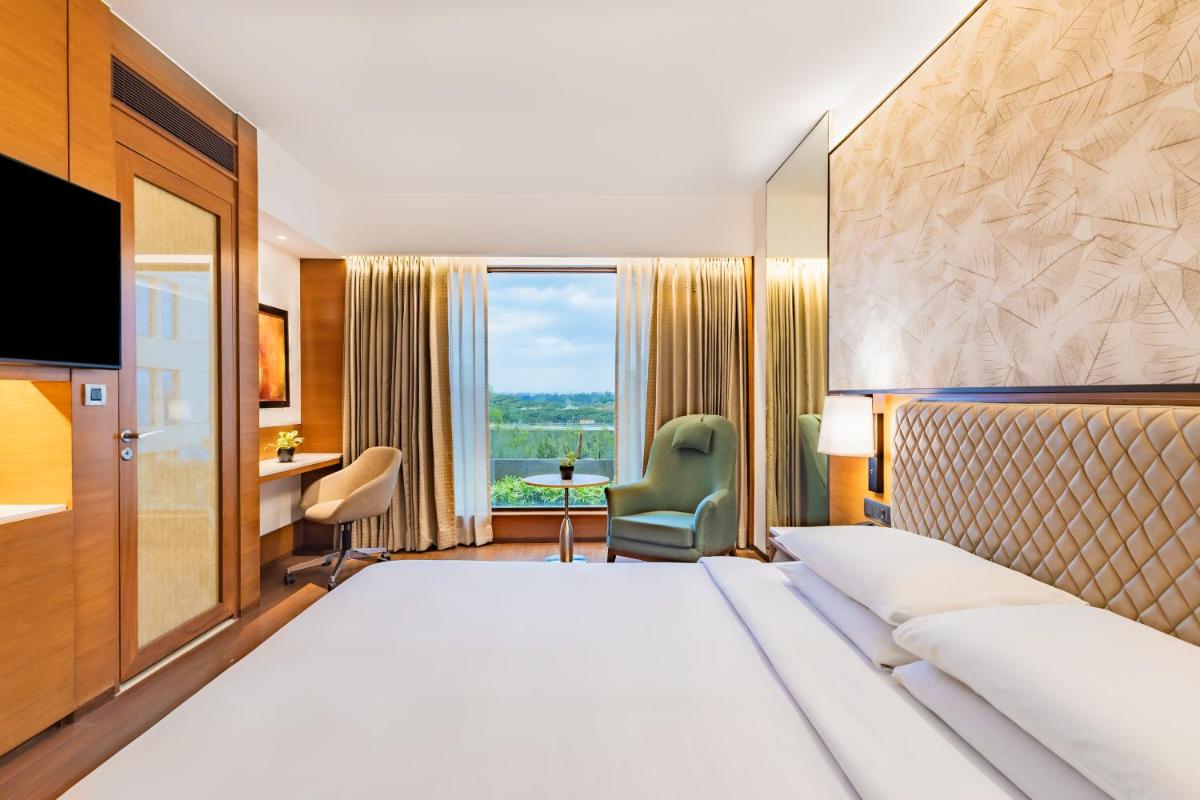 a hotel room with a large bed and a desk at Hyatt Pune in Pune