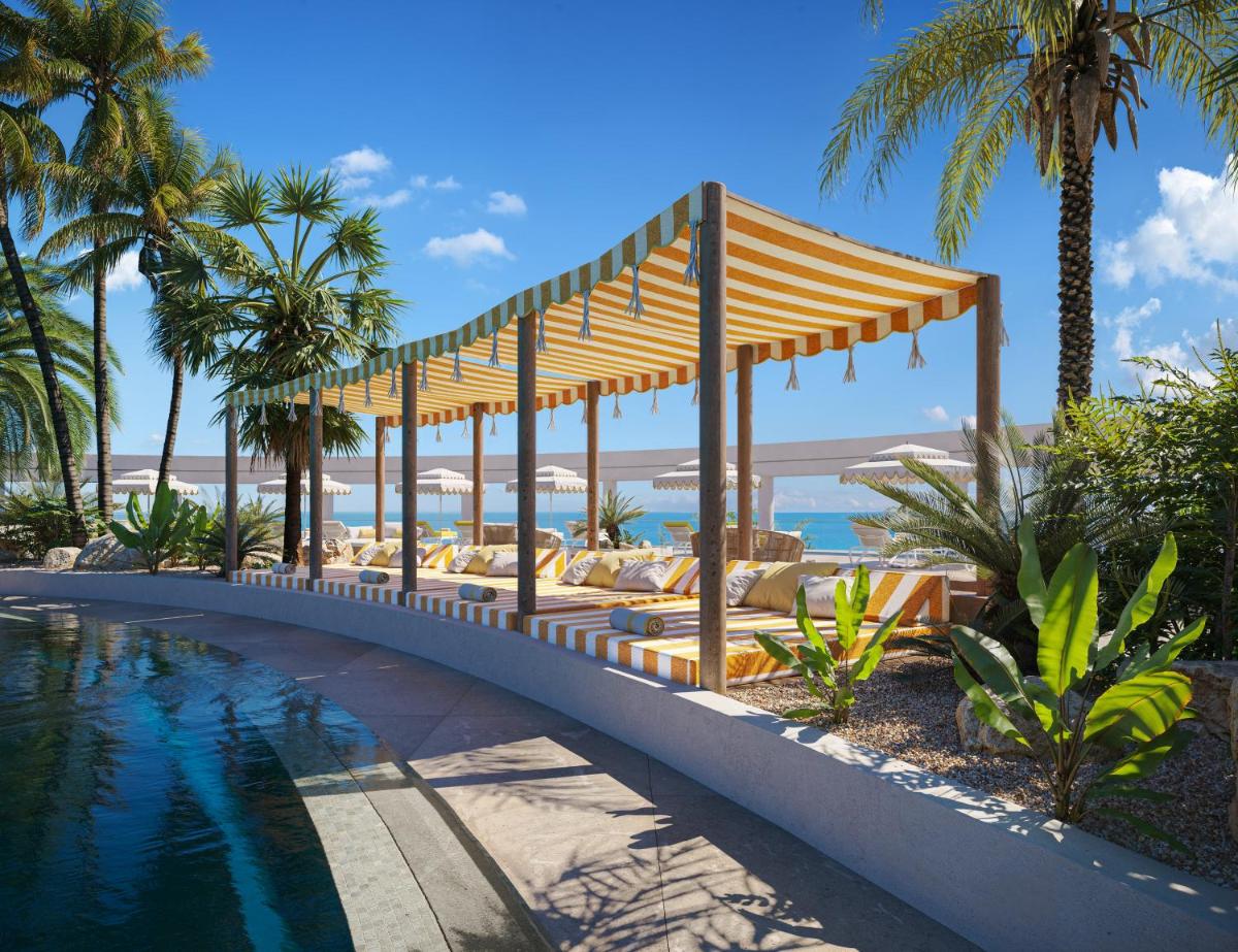 Un resort con piscina, sillas y palmeras. en Iberostar Selection Fuerteventura Palace, en Morro del Jable
