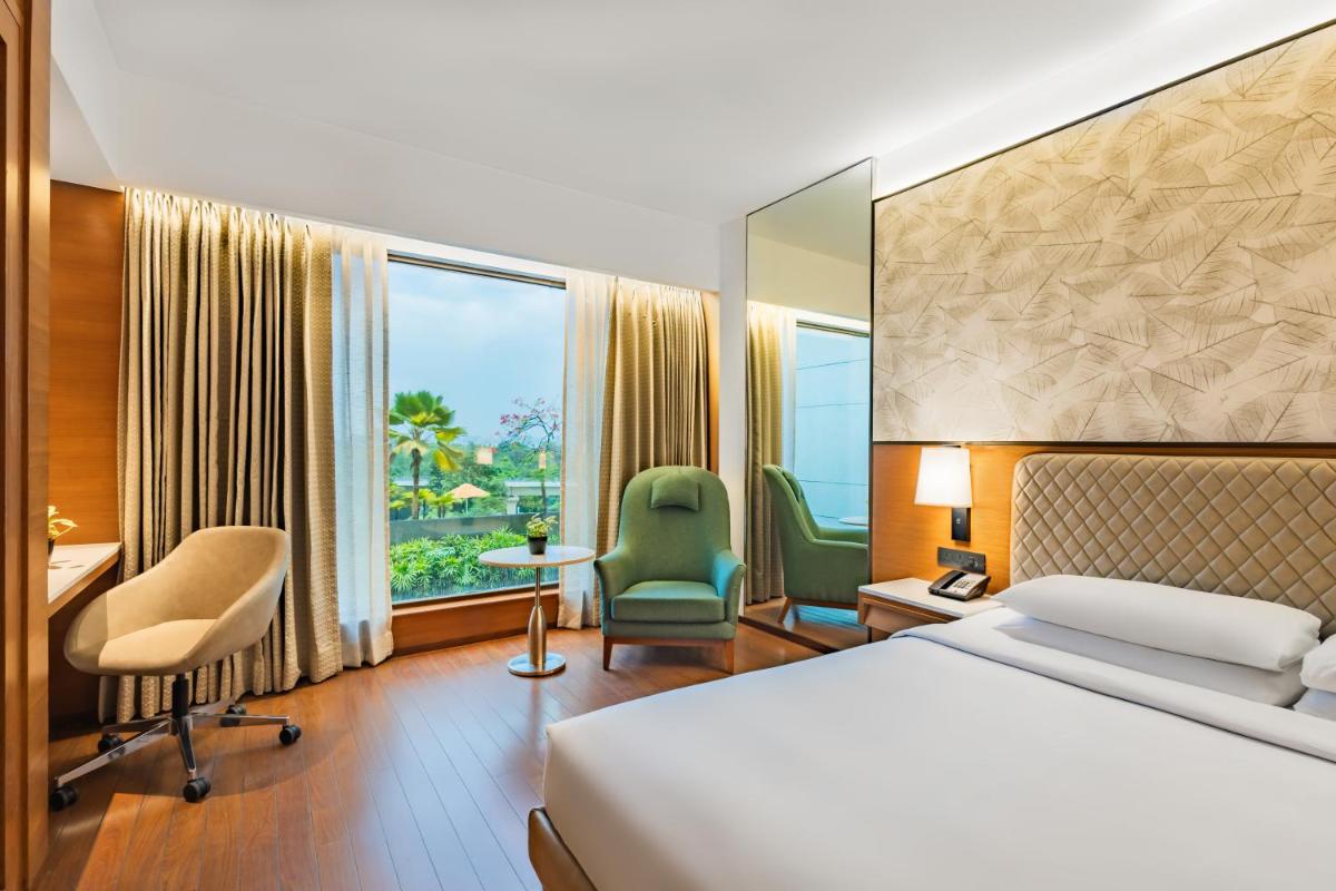 a hotel room with a bed and a desk and chairs at Hyatt Pune in Pune