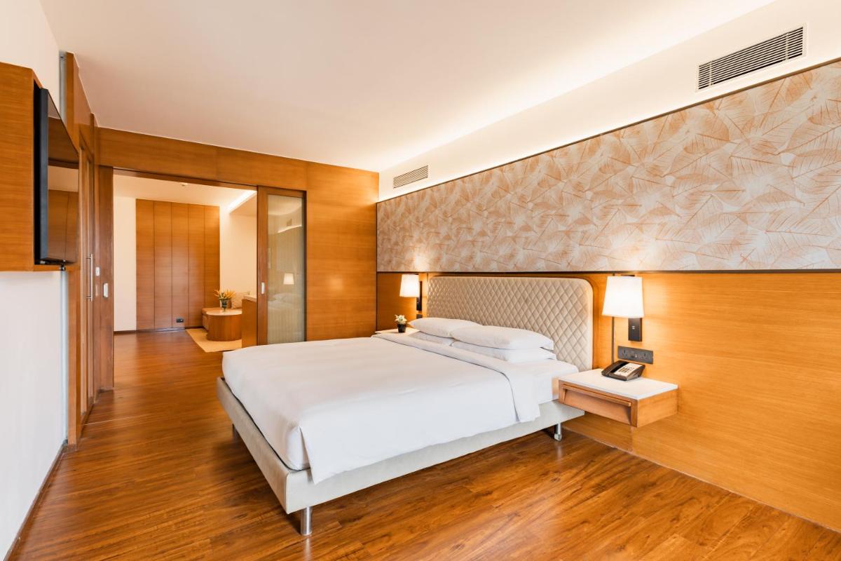 a bedroom with a large white bed and wooden floors at Hyatt Pune in Pune