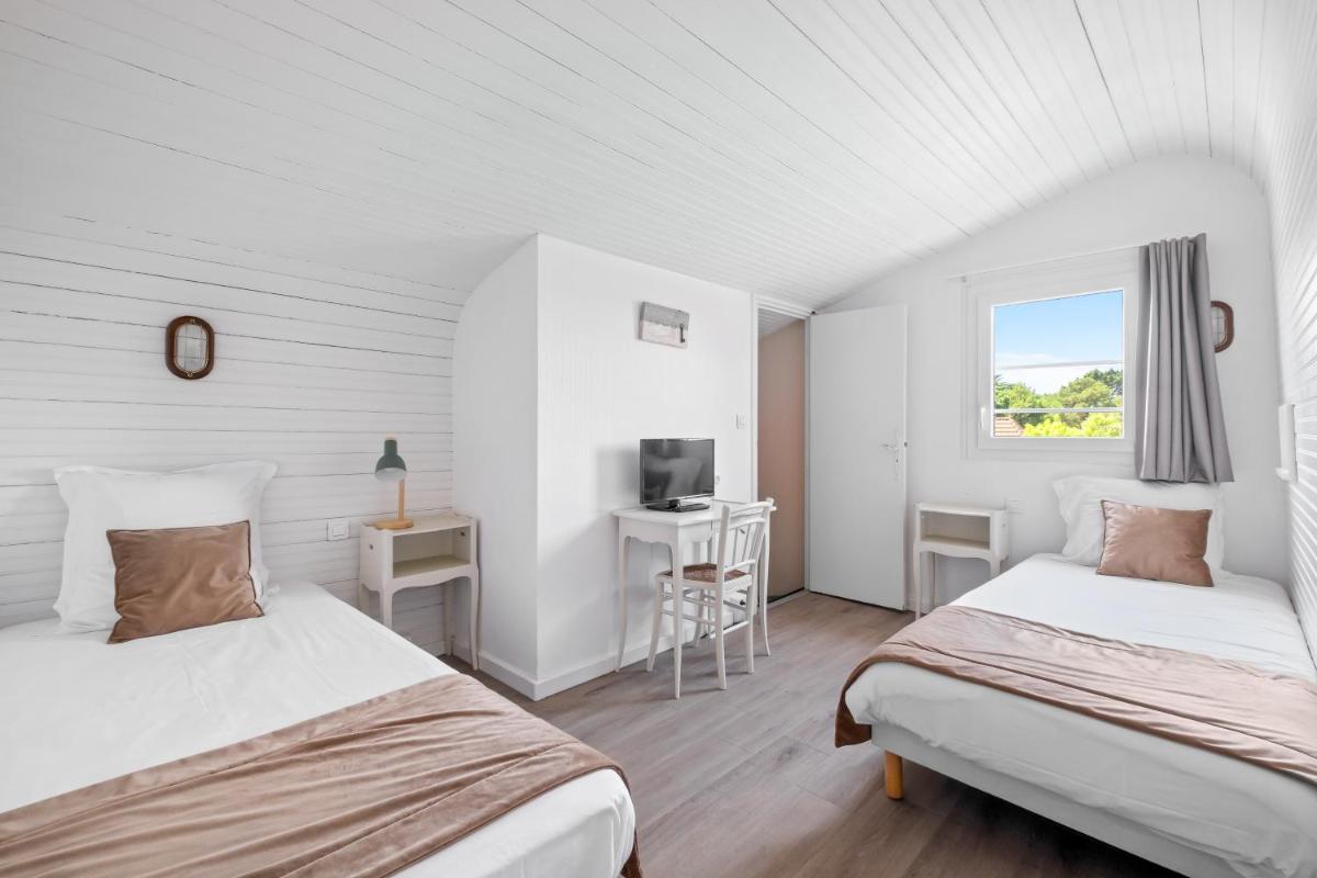 Cette chambre dispose de 2 lits, d'un bureau et d'une télévision. dans l'établissement Hotel Saint Paul, à Noirmoutier-en-l'lle