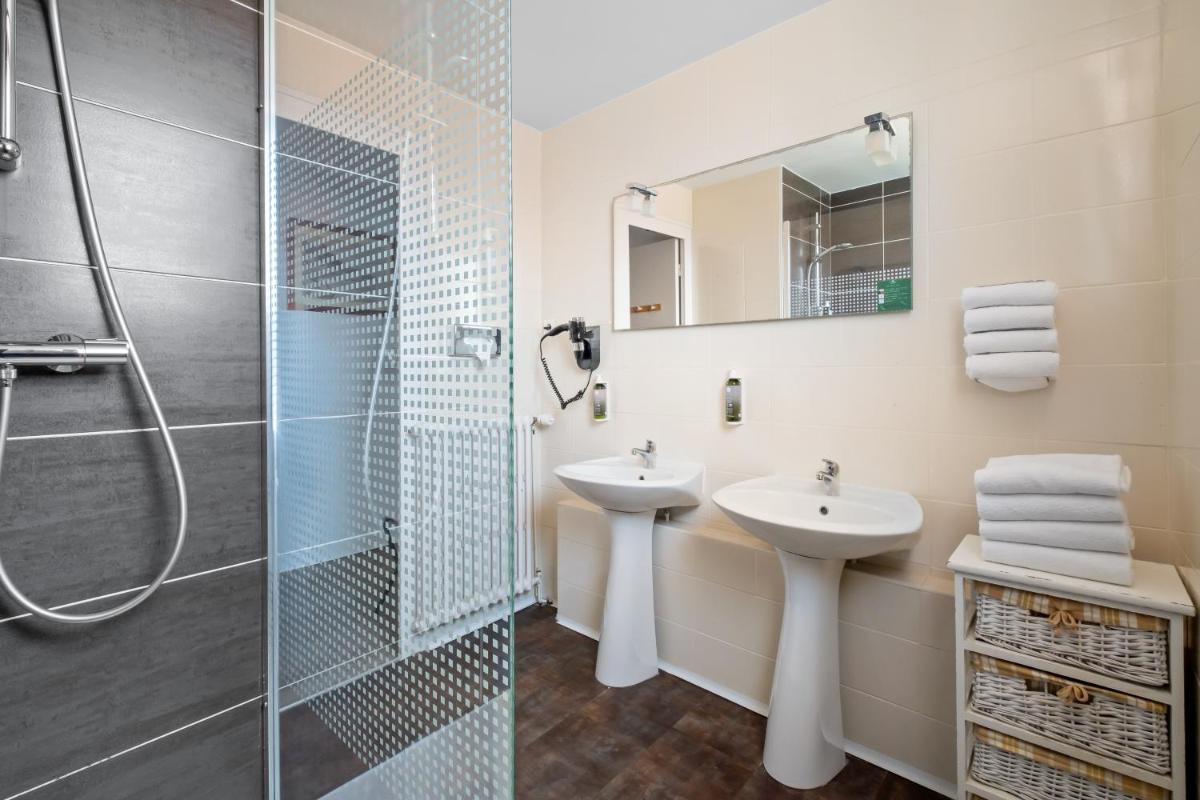 une salle de bain avec deux lavabos et une douche dans l'établissement Hotel Saint Paul, à Noirmoutier-en-l'lle