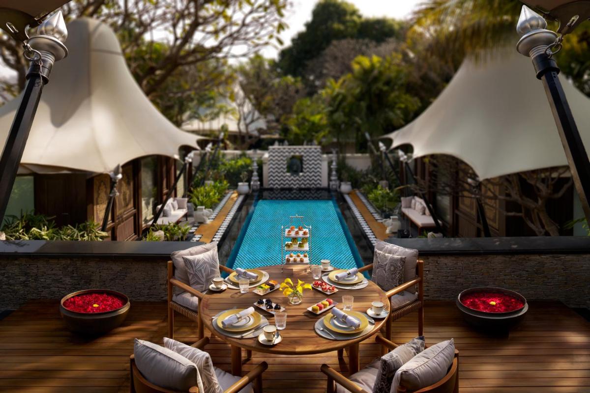 a table and chairs next to a swimming pool at The Leela Palace Udaipur in Udaipur