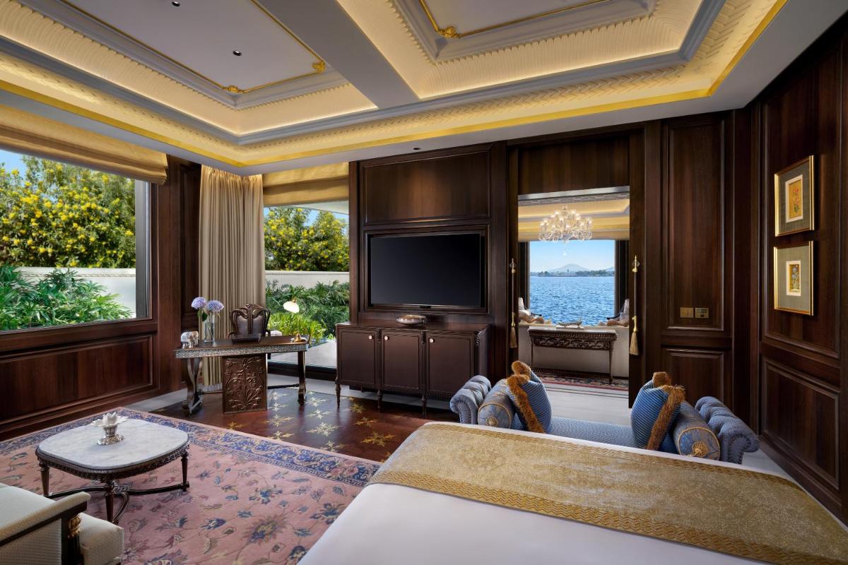a living room with a tv and a couch and chairs at The Leela Palace Udaipur in Udaipur