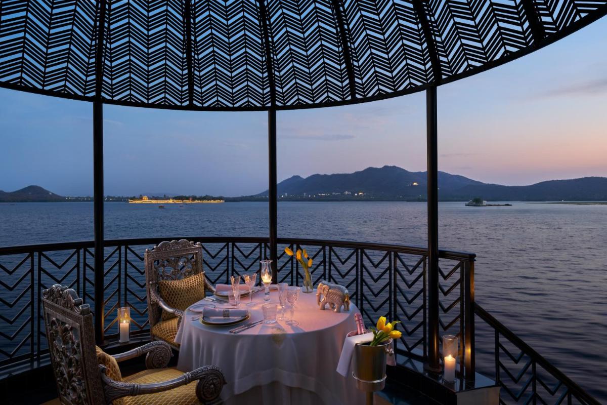 a table on a balcony with a view of the water at The Leela Palace Udaipur in Udaipur