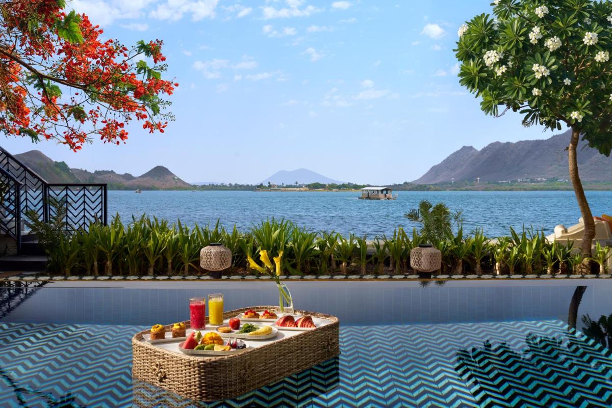 a table with fruit on it with a view of the water at The Leela Palace Udaipur in Udaipur
