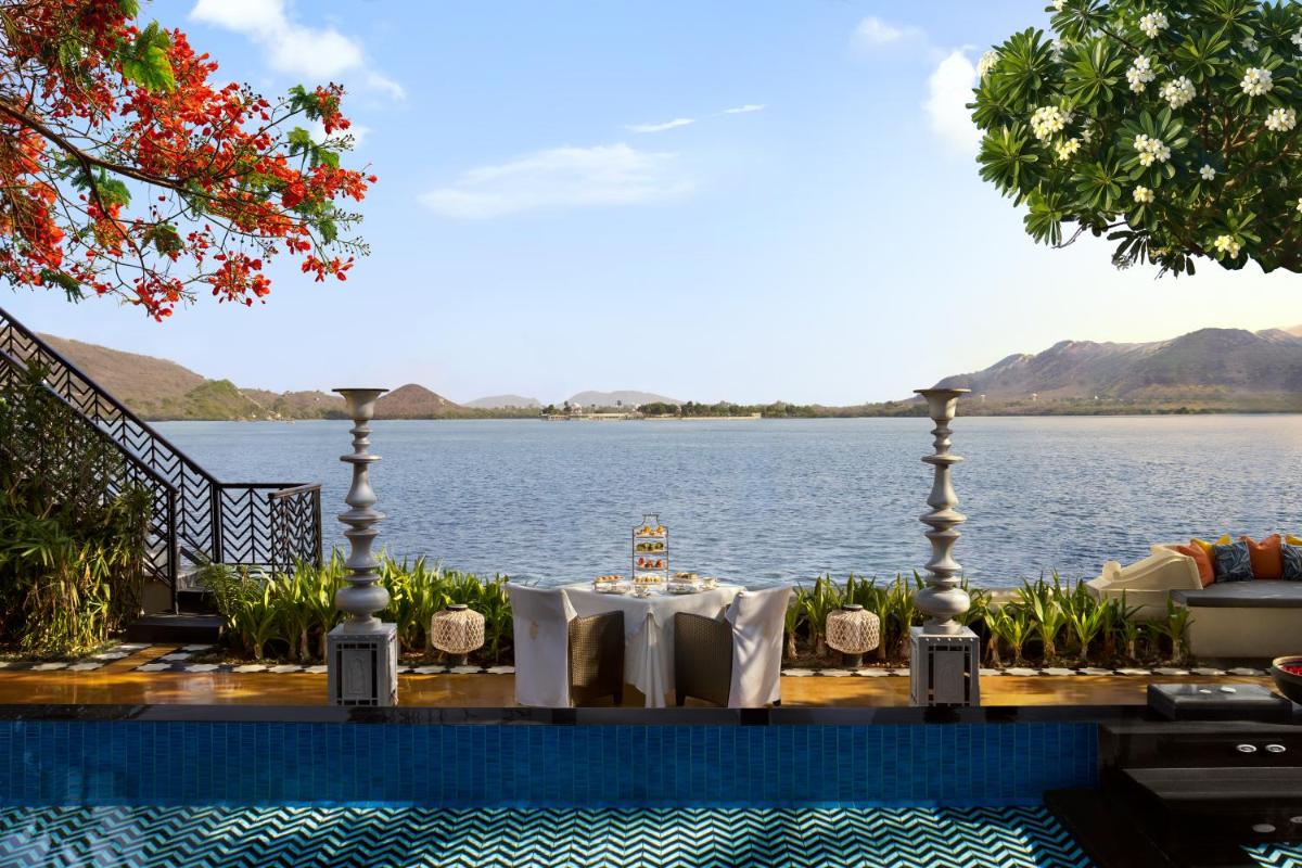 a dining table with a view of the water at The Leela Palace Udaipur in Udaipur