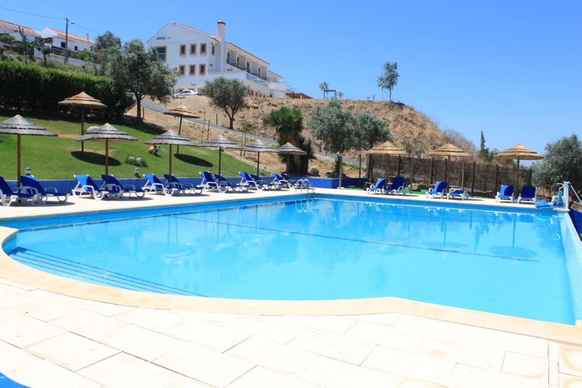 uma grande piscina com cadeiras e guarda-sóis em Hotel O Gato & Spa em Odivelas