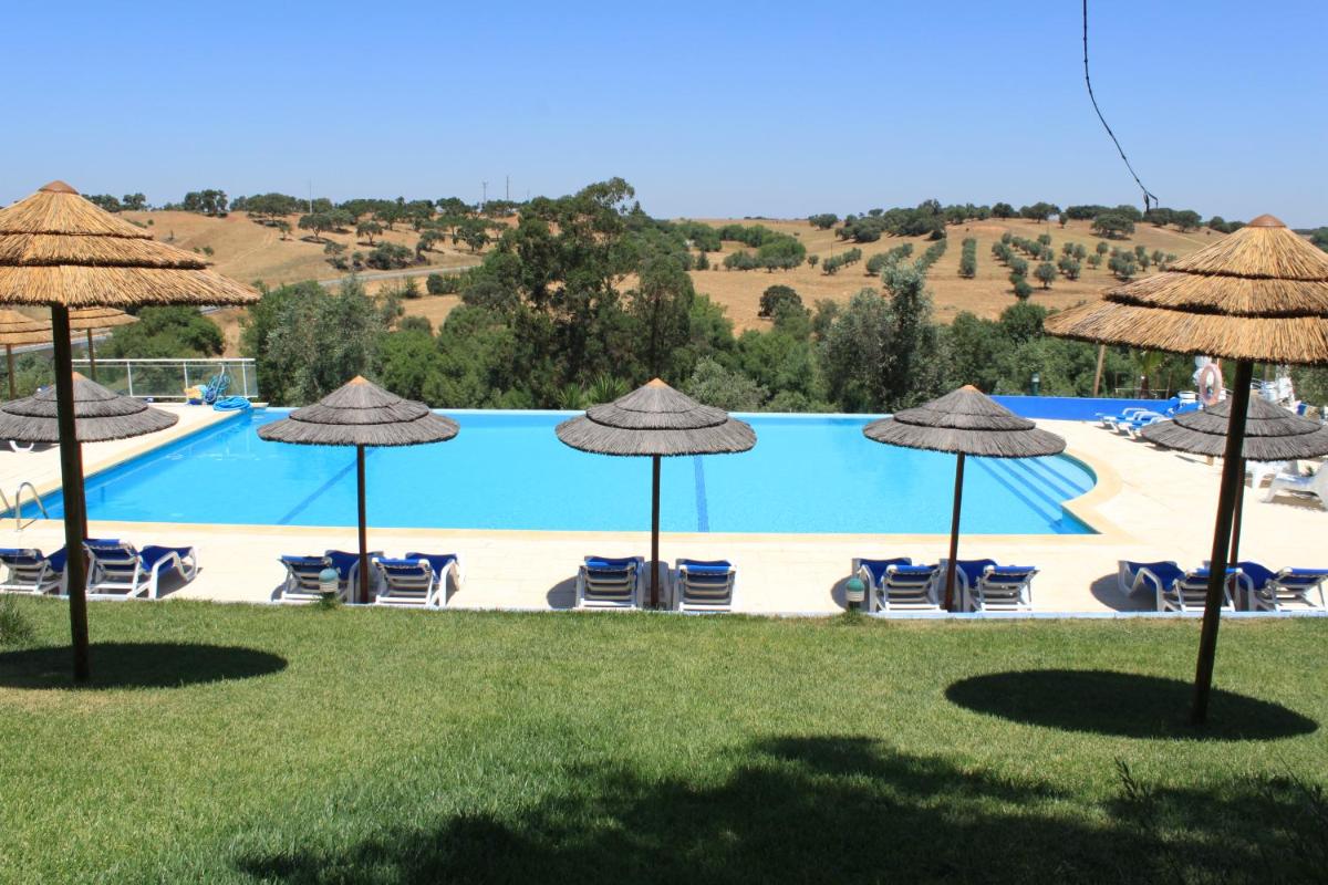 uma grande piscina com guarda-sóis e cadeiras em Hotel O Gato & Spa em Odivelas