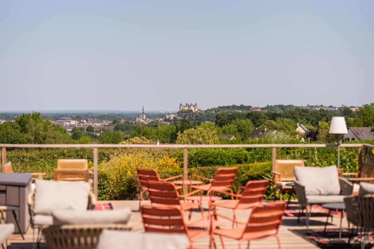 un groupe de chaises et de tables sur une terrasse dans l'établissement Les Terrasses de Saumur - Hôtel & Appartements - Restaurant & Spa (Logis), à Saumur