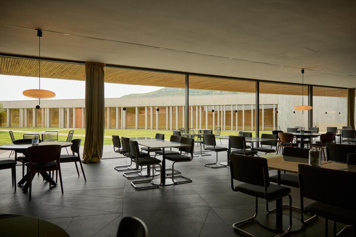 Un restaurante con mesas y sillas y un gran ventanal. en La Galiana Golf Resort - Adults Only, en Barraca de Aguas Vivas