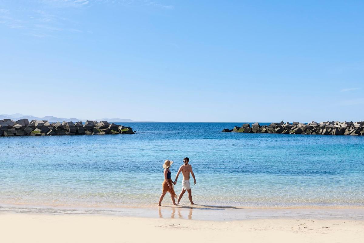 un hombre y una mujer caminando por la playa en Iberostar Selection Lanzarote Park, en Playa Blanca