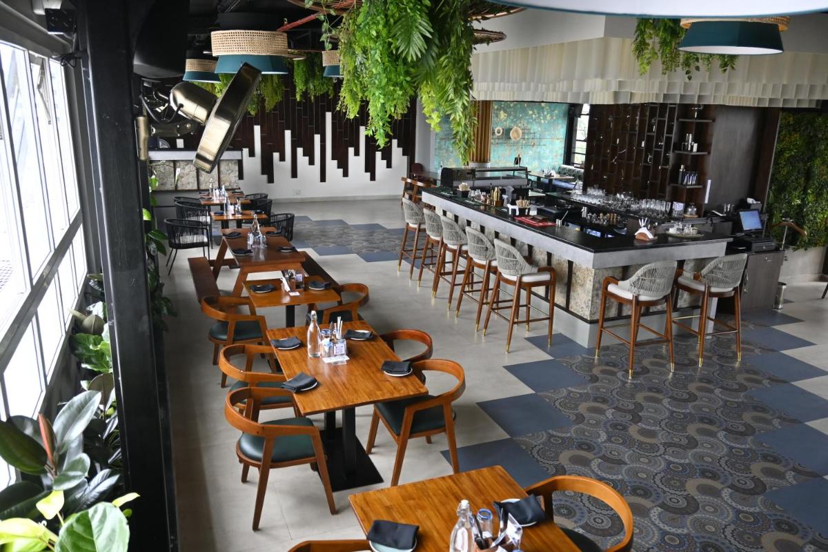 a restaurant with wooden tables and chairs and a bar at Fortune JP Palace, Mysore - Member ITC Hotels' Group in Mysore