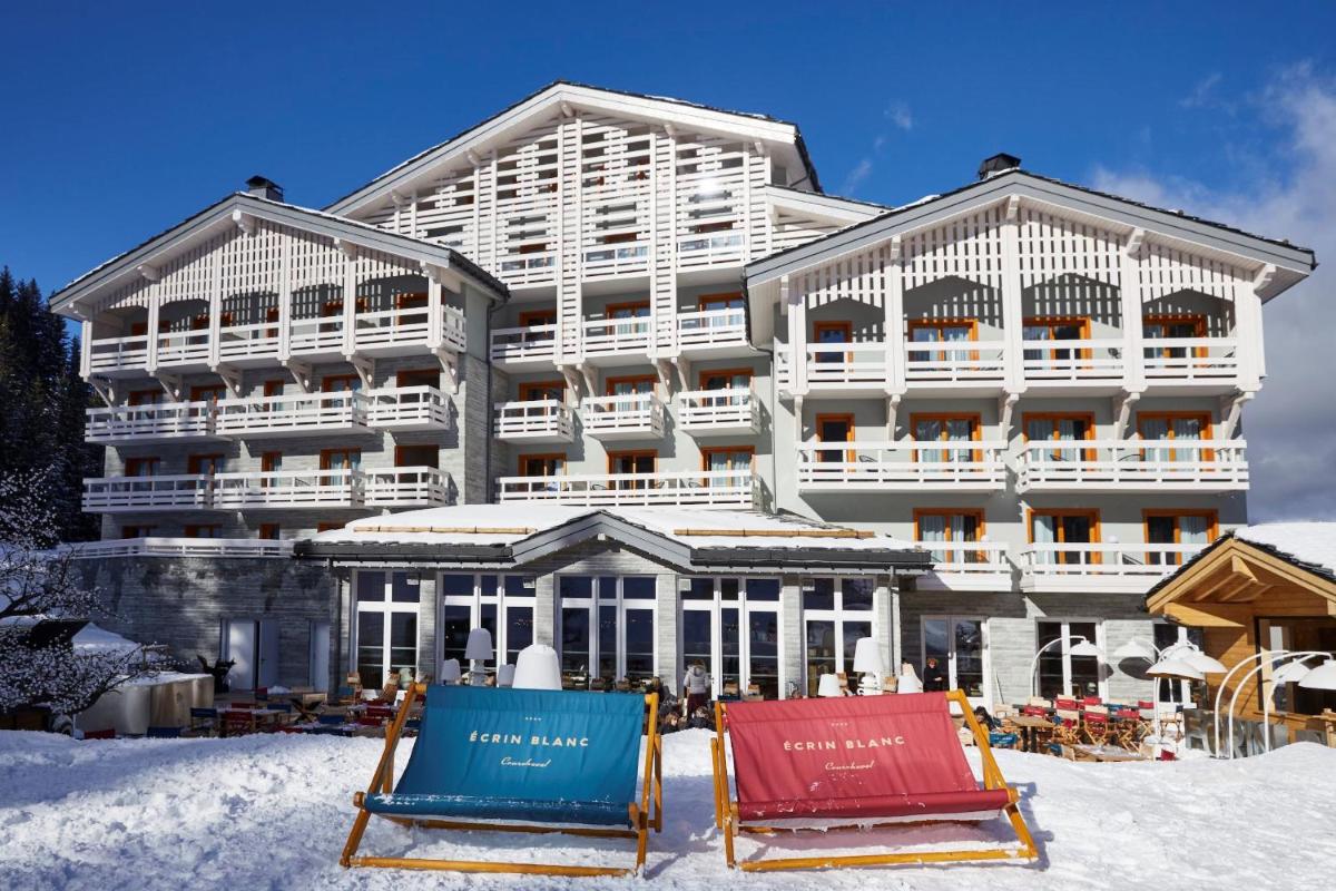 un hôtel sous la neige avec deux chaises devant dans l'établissement Ecrin Blanc Resort Courchevel - Aquapark, à Courchevel
