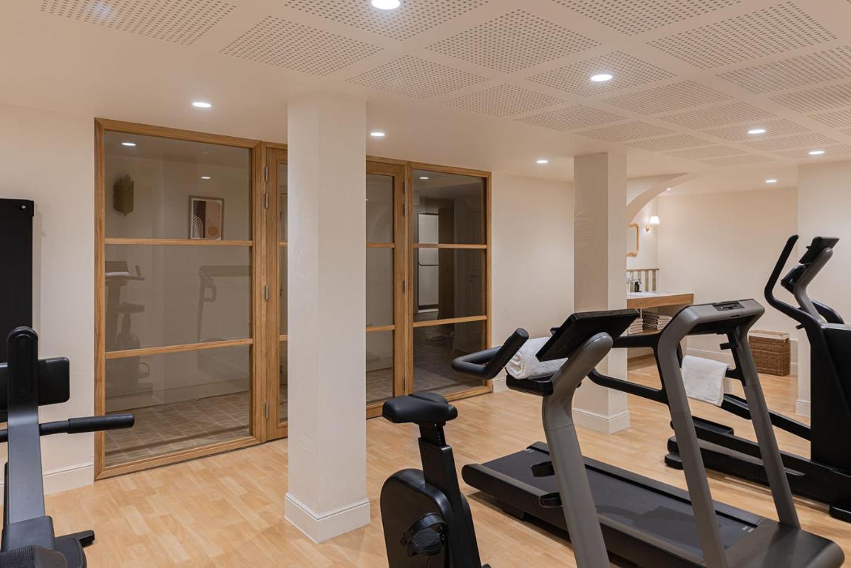 une salle de sport avec tapis de course et vélos elliptiques dans une pièce dans l'établissement Hôtel Maison Chiberta, à Anglet
