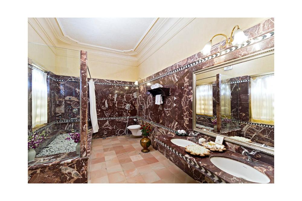 a bathroom with two sinks and a large mirror at Chunda Palace in Udaipur