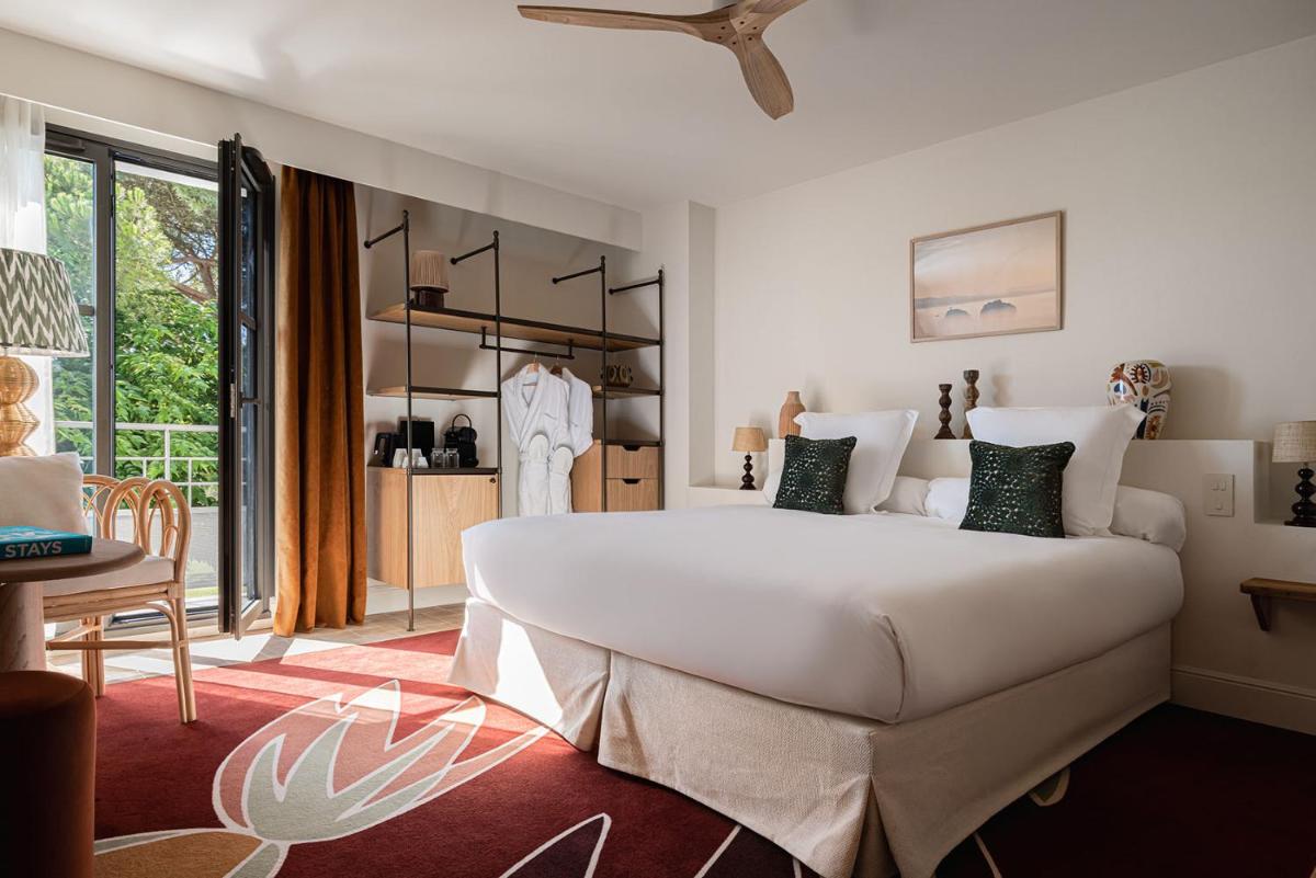 une chambre avec un grand lit blanc et une table dans l'établissement Hôtel Maison Chiberta, à Anglet