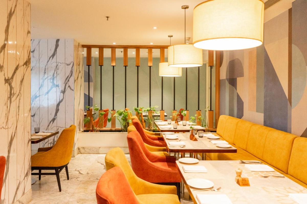a dining room with tables and yellow chairs at Radisson Blu Kochi in Cochin