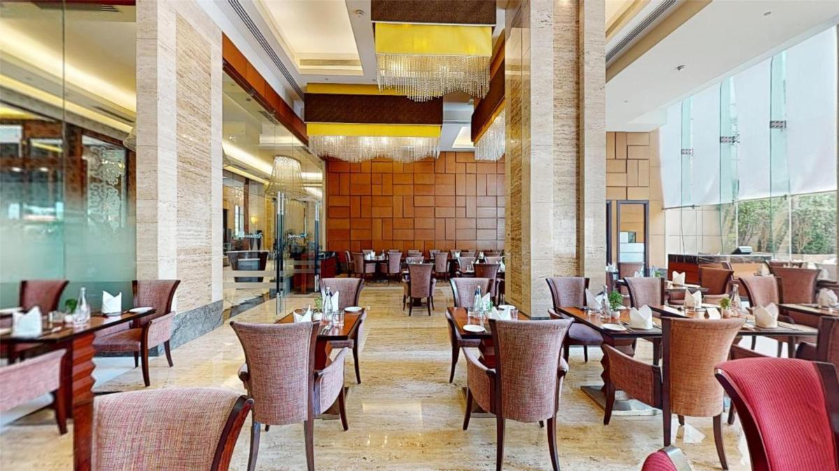 a restaurant with tables and chairs in a room at Radisson Blu Hotel, Nagpur in Nagpur