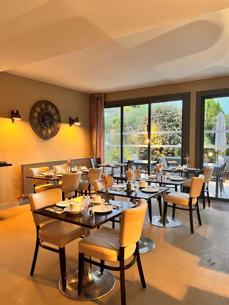 une salle à manger avec tables, chaises et fenêtres dans l'établissement Le Galet Hotel & Spa, à Saint-Philibert