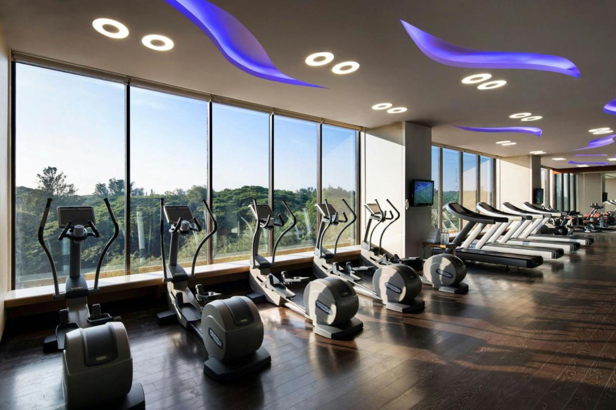 a gym with a row of treadmills and ellipticals at JW Marriott Hotel Bengaluru in Bengaluru