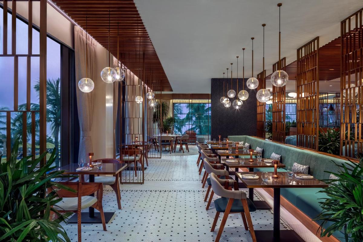 a restaurant with wooden tables and chairs and windows at JW Marriott Mumbai Juhu in Mumbai