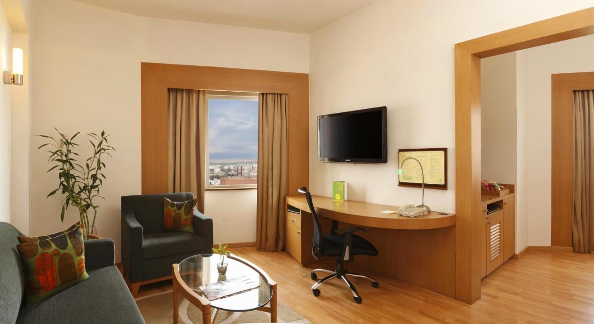 a hotel room with a desk and a tv at Lemon Tree Premier Hitec City Hyderabad in Hyderabad
