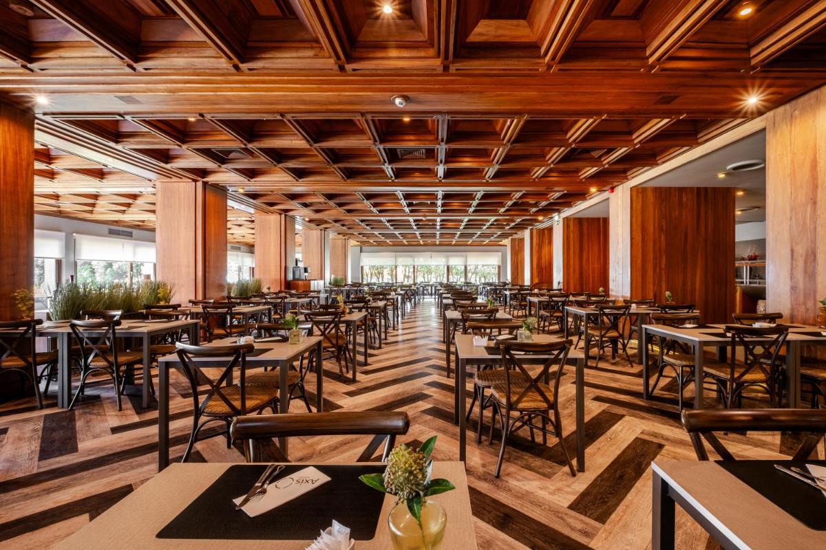 um restaurante com tetos, mesas e cadeiras de madeira em Axis Vermar Conference & Beach Hotel na Póvoa do Varzim